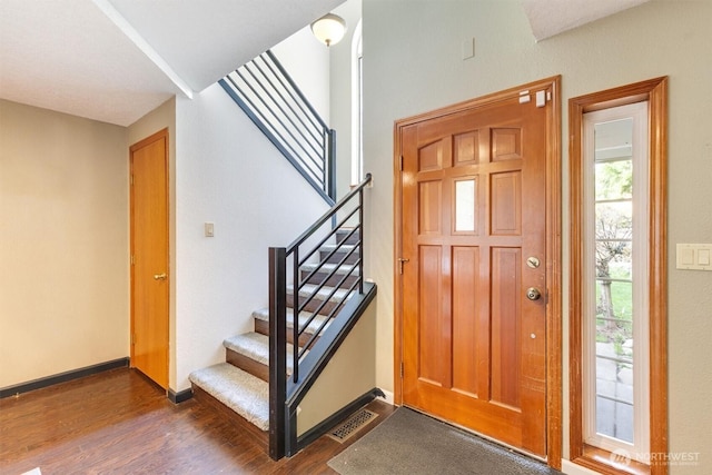 foyer featuring dark wood-style floors, visible vents, stairs, and baseboards