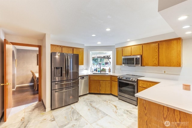 kitchen featuring brown cabinetry, appliances with stainless steel finishes, and a sink