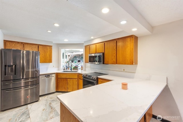 kitchen with brown cabinets, a peninsula, stainless steel appliances, and a sink