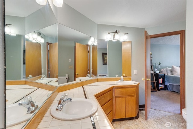 ensuite bathroom featuring double vanity, toilet, ensuite bathroom, and a sink