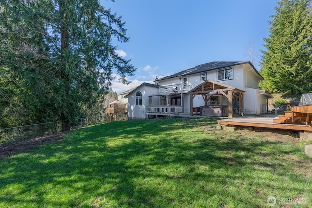 rear view of house with a wooden deck, fence, a lawn, and a hot tub