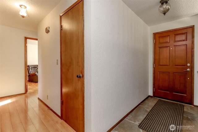 interior space featuring light wood finished floors, baseboards, and a textured ceiling