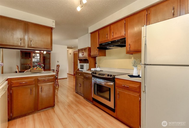 kitchen featuring light wood finished floors, light countertops, brown cabinetry, white appliances, and under cabinet range hood