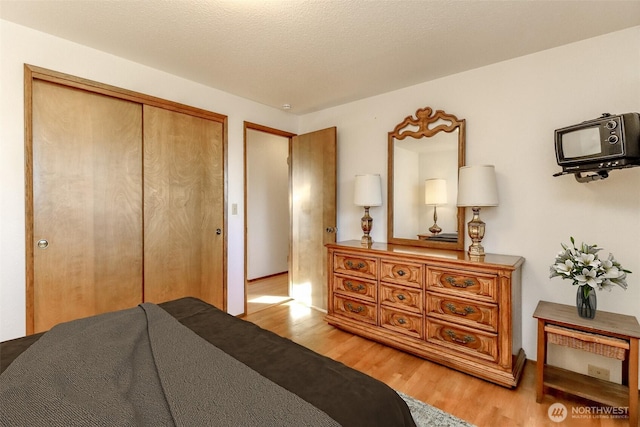 bedroom featuring light wood-type flooring, a closet, and a textured ceiling