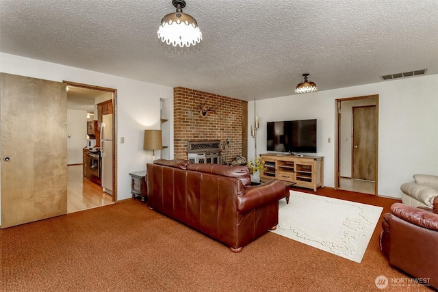 carpeted living room with a textured ceiling, a fireplace, and visible vents