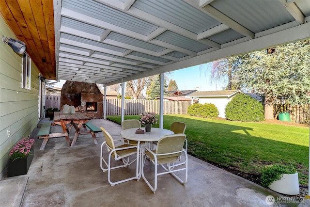 view of patio / terrace featuring an outdoor brick fireplace, outdoor dining area, and a fenced backyard