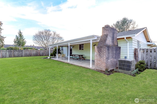 back of property with a patio, a chimney, fence, a yard, and central AC