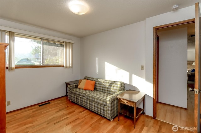 living area featuring visible vents and wood finished floors