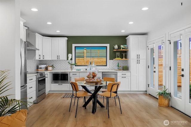 kitchen with appliances with stainless steel finishes, white cabinets, light countertops, and light wood finished floors