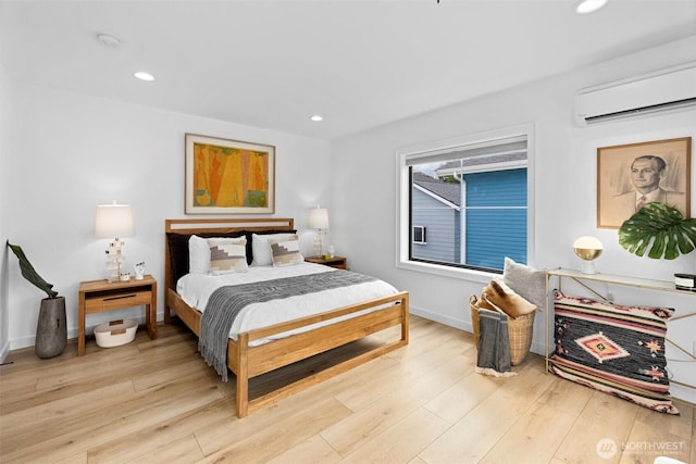 bedroom with a wall unit AC, light wood finished floors, baseboards, and recessed lighting