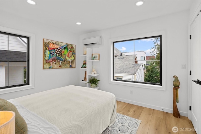 bedroom with light wood-type flooring, recessed lighting, baseboards, and a wall mounted air conditioner