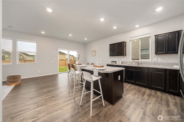 kitchen with a sink, a kitchen island, a breakfast bar, and recessed lighting