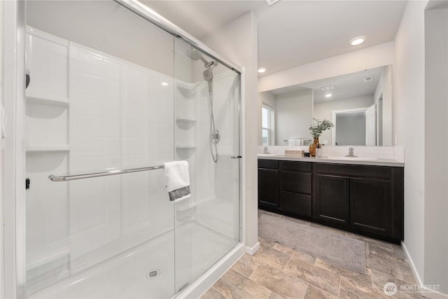 bathroom with baseboards, double vanity, recessed lighting, a stall shower, and a sink