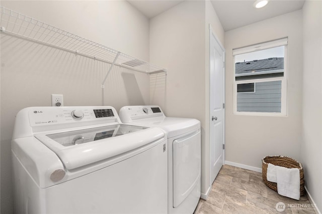 washroom featuring laundry area, stone finish floor, baseboards, and independent washer and dryer