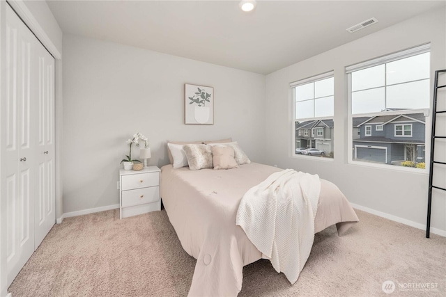 carpeted bedroom featuring a closet, visible vents, and baseboards