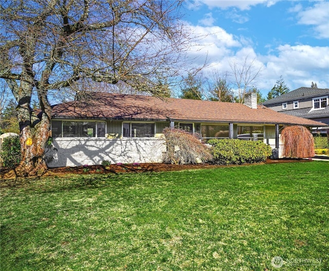 ranch-style house featuring a chimney and a front lawn