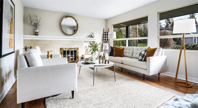 living room featuring baseboards, wood finished floors, and a tile fireplace