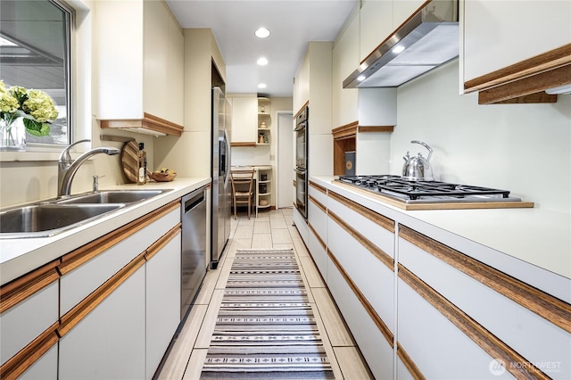 kitchen with wall chimney range hood, light countertops, recessed lighting, appliances with stainless steel finishes, and a sink