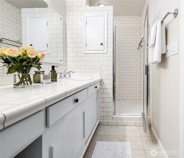 bathroom with a stall shower, backsplash, tile walls, tile patterned flooring, and vanity