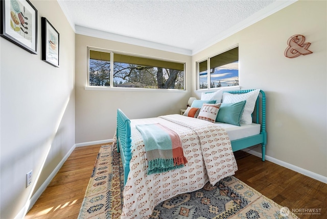 bedroom featuring a textured ceiling, baseboards, and wood finished floors