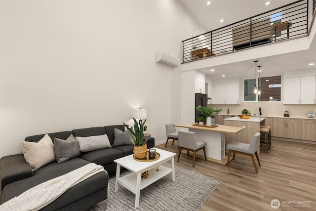 living area featuring a towering ceiling, light wood finished floors, recessed lighting, and a wall mounted air conditioner