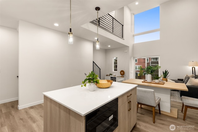 kitchen with black microwave, light countertops, a kitchen island, and light wood-style flooring