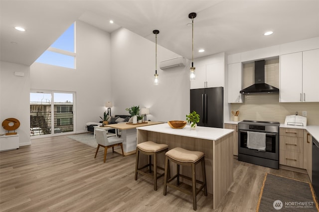 kitchen featuring black appliances, wall chimney exhaust hood, a kitchen breakfast bar, and light countertops