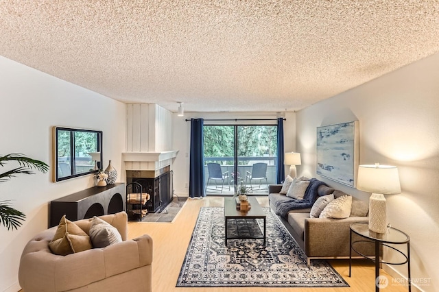 living room with a textured ceiling, wood finished floors, and a tile fireplace