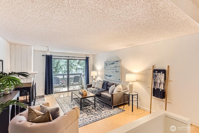 living room featuring a textured ceiling, baseboards, wood finished floors, and a multi sided fireplace