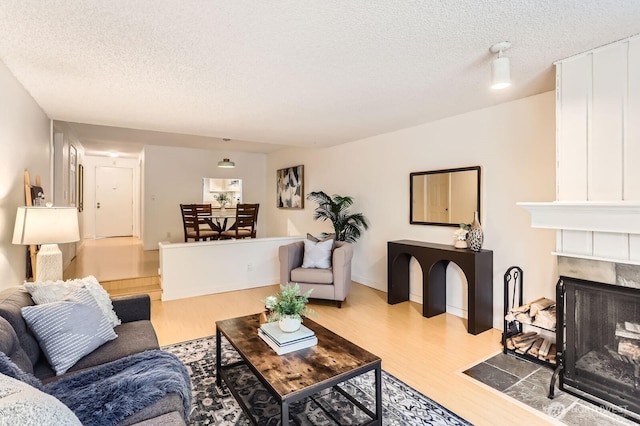 living room featuring a textured ceiling, wood finished floors, and a high end fireplace