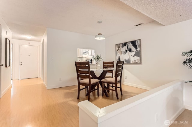 dining space with light wood finished floors, baseboards, and visible vents