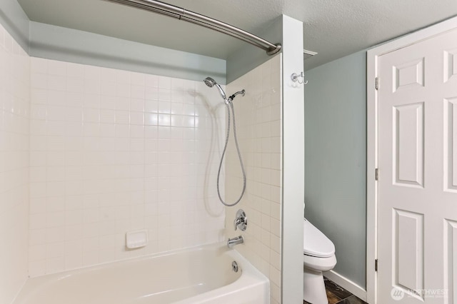 full bathroom featuring baseboards, a textured ceiling, toilet, and bathing tub / shower combination