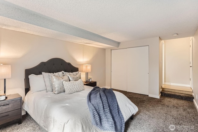 carpeted bedroom featuring a closet, a textured ceiling, and baseboards