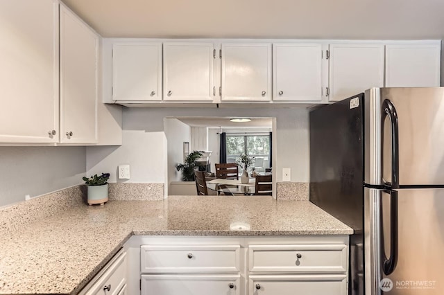 kitchen featuring white cabinetry, light stone counters, and freestanding refrigerator