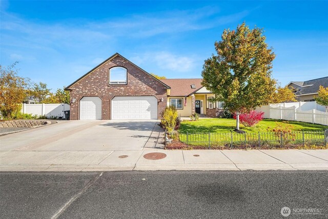 view of front of house featuring a fenced front yard, a front yard, concrete driveway, and brick siding