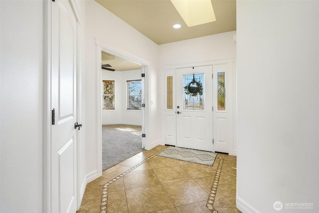 entryway featuring a skylight, tile patterned flooring, baseboards, and recessed lighting