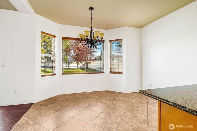 unfurnished dining area featuring an inviting chandelier, baseboards, and light tile patterned flooring