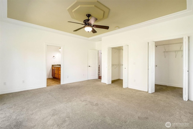 unfurnished bedroom with carpet floors, baseboards, ensuite bath, and two closets