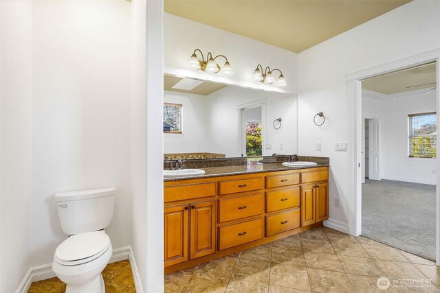 full bath with baseboards, a sink, toilet, and double vanity