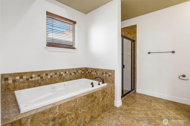 bathroom with a stall shower, baseboards, and a bath