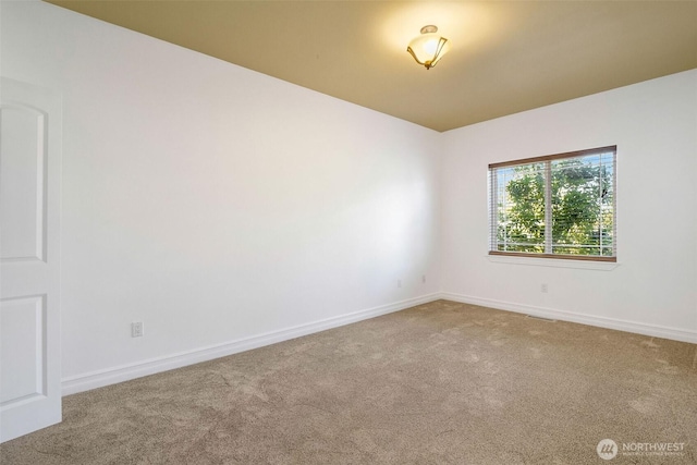 carpeted empty room featuring baseboards