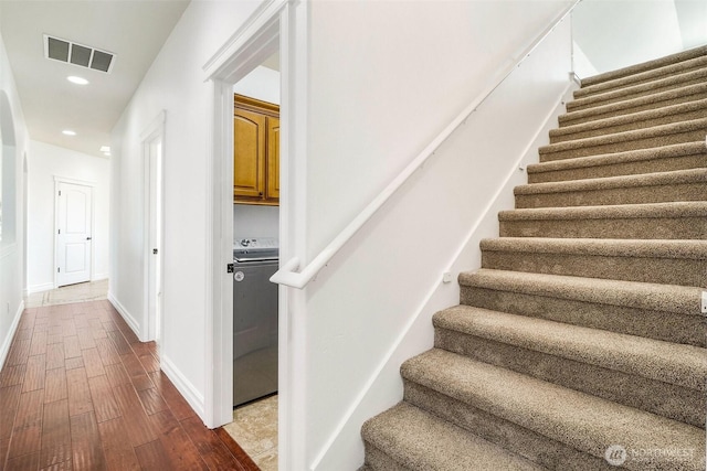 stairway featuring recessed lighting, visible vents, hardwood / wood-style floors, washer / dryer, and baseboards