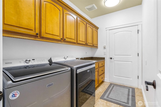 clothes washing area with cabinet space, light tile patterned flooring, and washing machine and clothes dryer