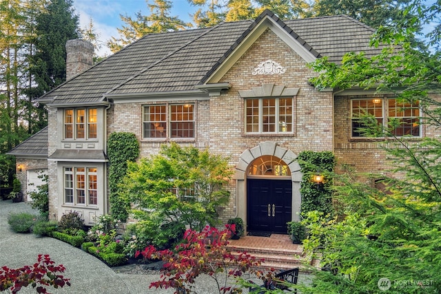 view of front of home featuring a chimney and brick siding