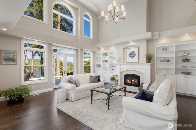 living room featuring built in shelves, baseboards, french doors, dark wood-style floors, and a tiled fireplace