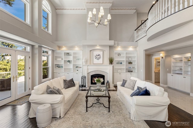 living area featuring ornamental molding, a lit fireplace, built in shelves, and wood finished floors