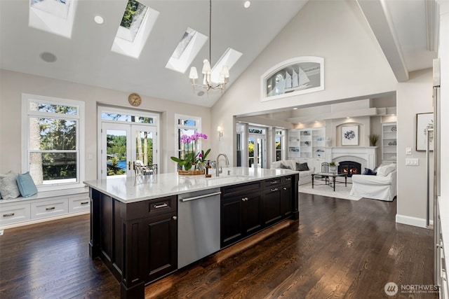 kitchen with a warm lit fireplace, open floor plan, french doors, stainless steel dishwasher, and a sink