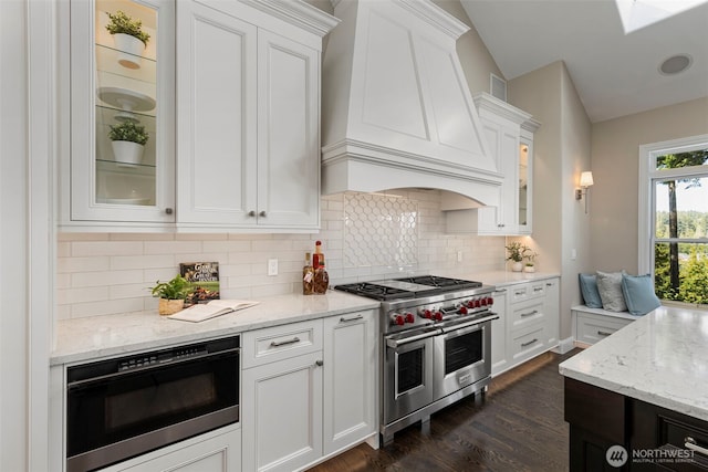 kitchen with custom range hood, glass insert cabinets, white cabinets, built in microwave, and double oven range