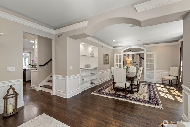 dining room featuring stairs, arched walkways, wood finished floors, and a decorative wall