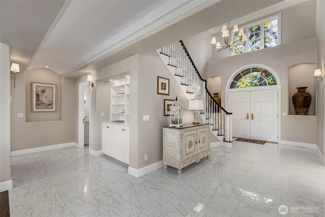 entryway with marble finish floor, a notable chandelier, baseboards, and stairs